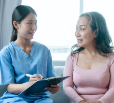 Lady holding a clip board looking at elderly woman