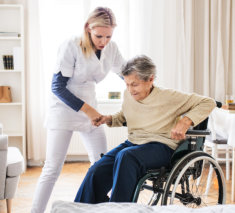 Lady helping elderly woman to stand up