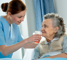 lady giving elderly woman her medicine