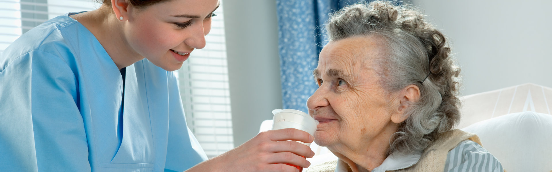 lady giving elderly her medicine